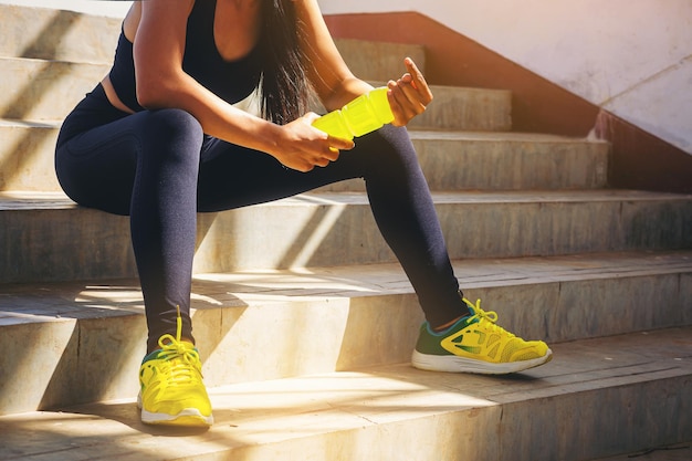 Tired runner woman with a bottle of electrolyte drink freshness after training outdoor workout