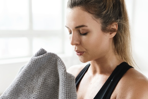 Photo tired sweaty woman with a towel after fitness workout in the gym