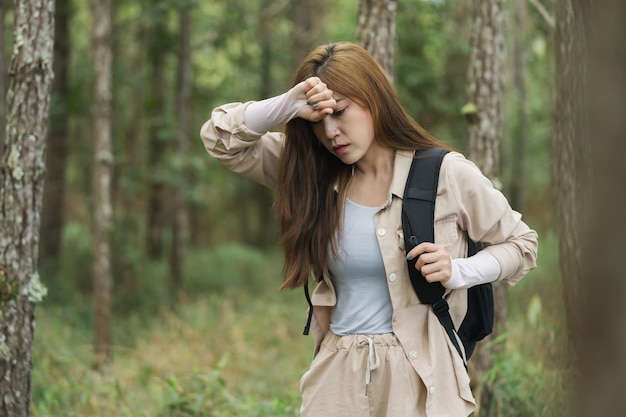 Tired woman carrying a backpack travel and walking in the forest