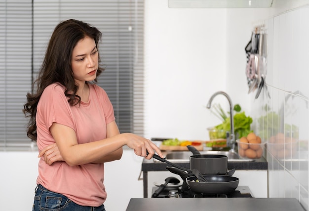 Tired woman cooking and preparing food in the kitchen at home