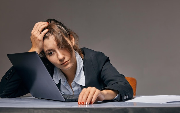 Photo a tired woman sits at a table in front of a laptop