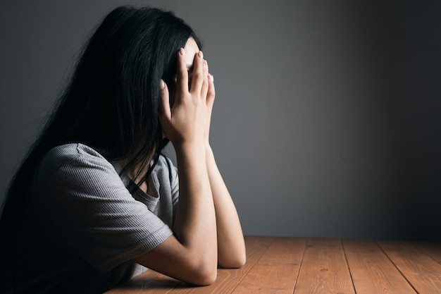 Tired woman sitting at the table covering her face