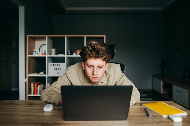 tired worker at a remote work at home sitting at work in the bedroom and looking at the laptop