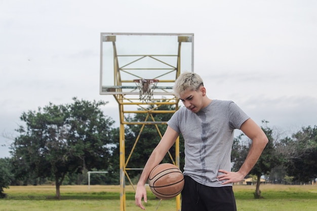 Tired young man on an abandoned basketball court.