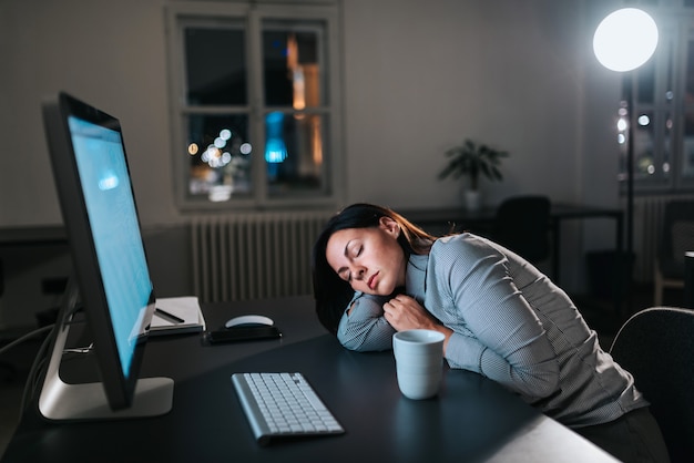 Tired young woman fall asleep while working overtime.