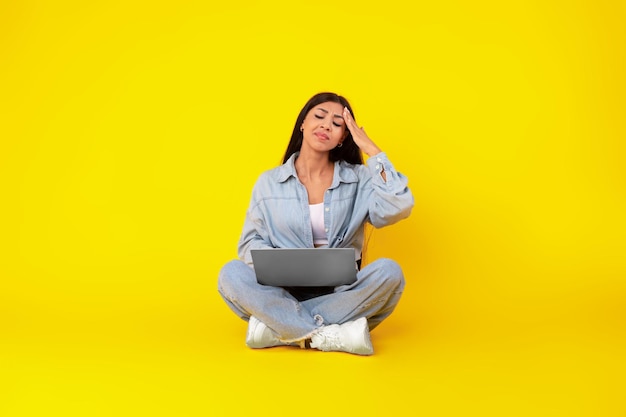 Tired young woman sitting on floor with pc