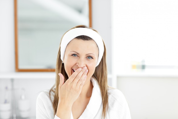 Tired young woman yawning in the bathroom looking at the camera 