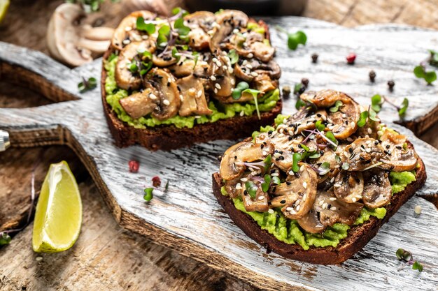 Toast avocado mushrooms and microgreen whole grain sandwich Decorated with sesame Vegetarian food Vegan menu Delicious breakfast or snack Clean eating dieting vegan food concept top view