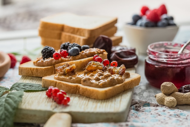 toast bread with homemade strawberry jam and peanut butter served with berry. Homemade toast bread with jam and peanut butter on wood table for breakfast. Delicious toast bread ready to served.