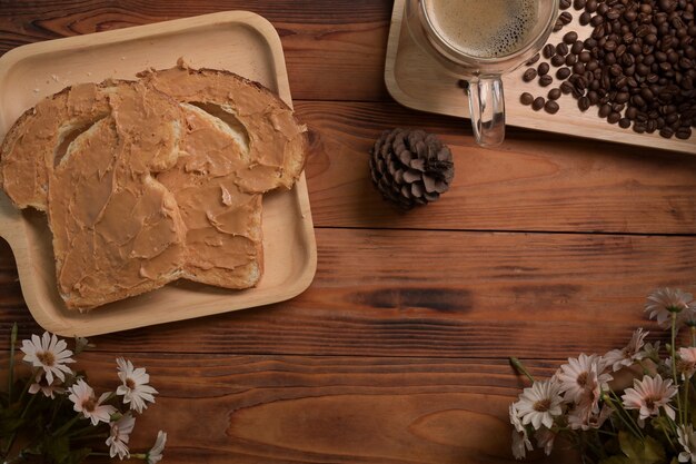 Toast bread with peanut butter and coffee cup on wooden table.