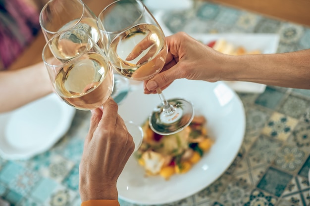 Toast. Close up picture of galsses with wine in hands of friends