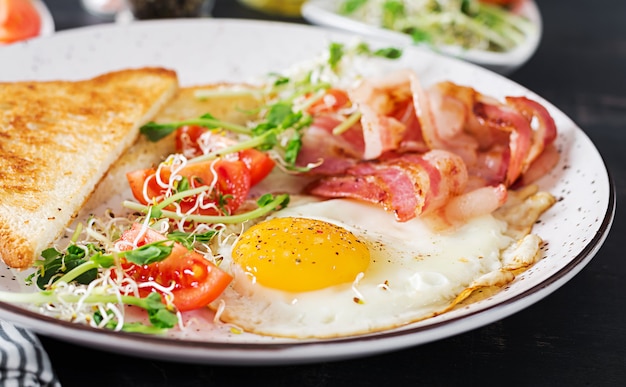 toast, egg, bacon and tomatoes and microgreens salad.