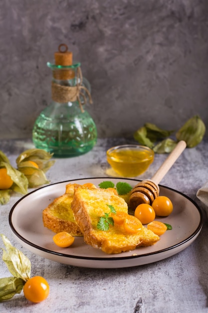 Toast fried in egg with physalis honey and mint on a plate Homemade dessert Vertical view