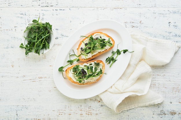 Toast or sandwich with cream cheese and micro greens peas and sunflower Concept healthy food or snack Flat lay copy space