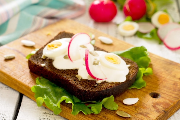 Toast sandwich with egg, radish, pumpkin seeds and sour cream, selective focus.