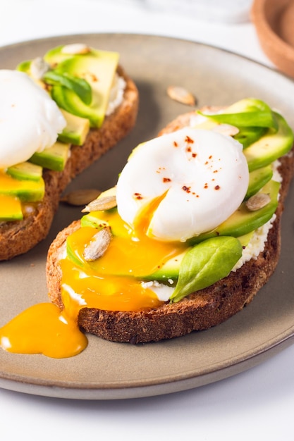 Toast with avocado, soft cream cheese, rye bread and poached Egg.