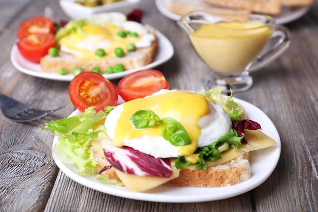 Toast with egg Benedict and tomato on plate on wooden table