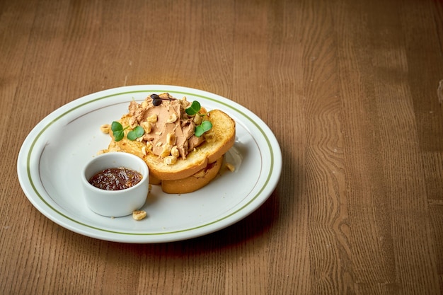 Toast with pate and nuts in a plate on a wooden background