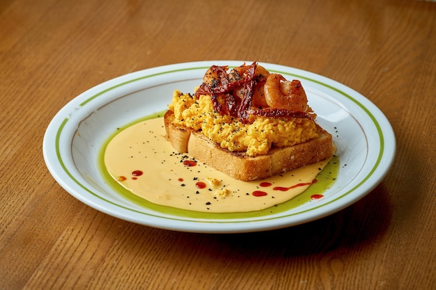 Toast with scrambled eggs and shrimps in a white plate