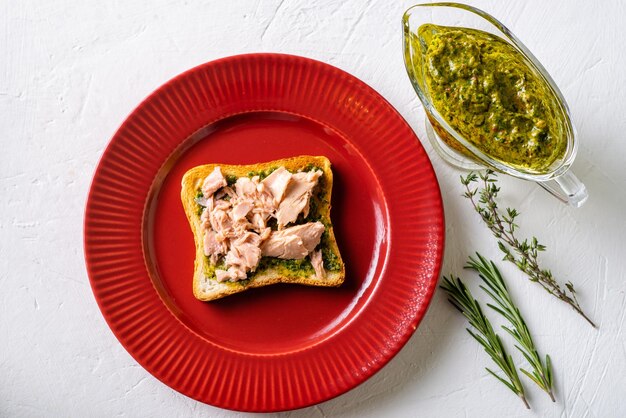 Photo toast with tuna and chimichurri sauce on a red plate white background