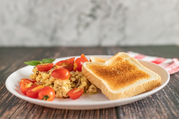 Toasted bread with scrambled eggs and cherry tomato