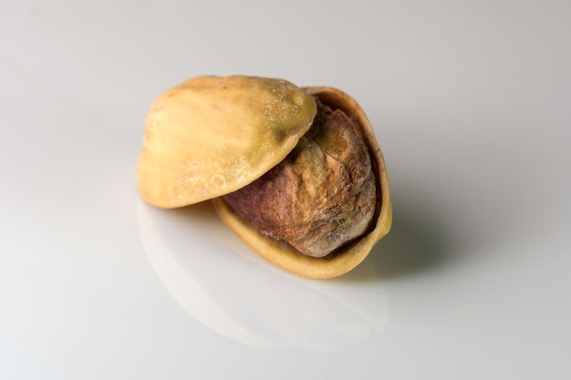 Toasted salted pistachio nuts on white reflective background close-up macro photography