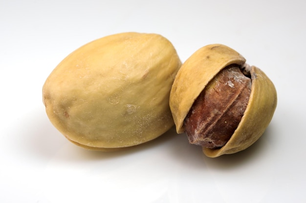 Toasted salted pistachio nuts on white reflective background close-up macro photography