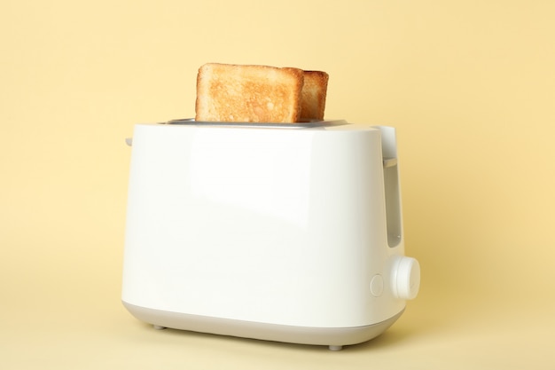 Toaster with bread slices on beige, close up