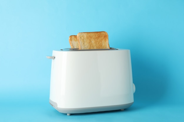 Toaster with bread slices on blue background, space for text