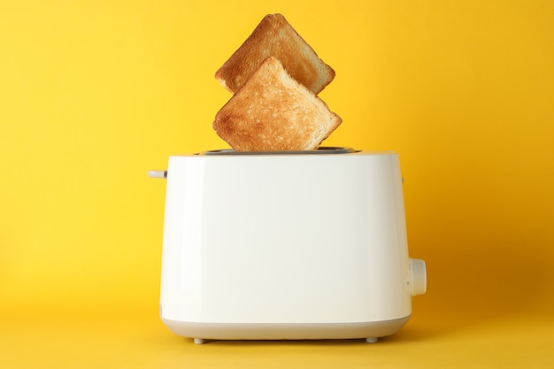 Toaster with bread slices on yellow background, space for text