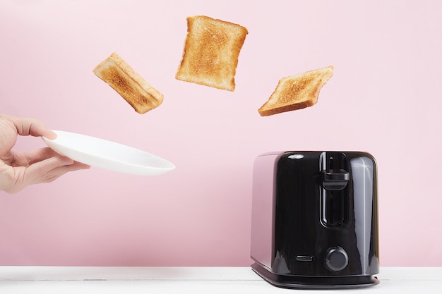 Photo toasts flew out of modern toaster. near glass of milk. levitation food and dish. delicious morning breakfast concept