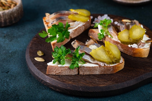 Toasts with bread herring pickled cucumber and cream cheese Smorrebrod Danish food Sandwich with herring Healthy breakfast