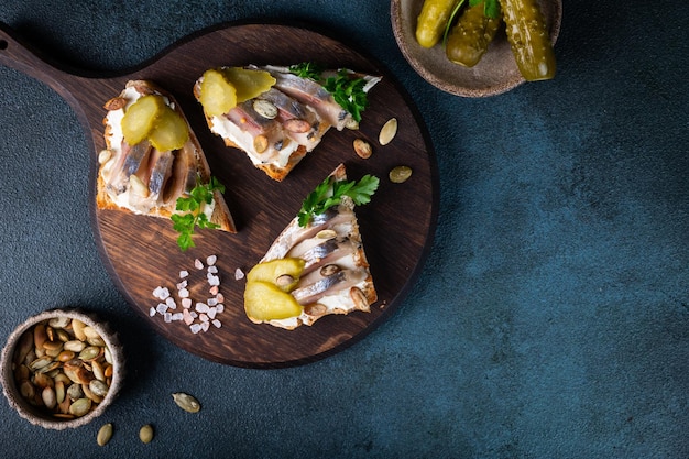 Toasts with bread herring pickled cucumber and cream cheese Smorrebrod with herring Danish food Sandwich with herring Healthy breakfast