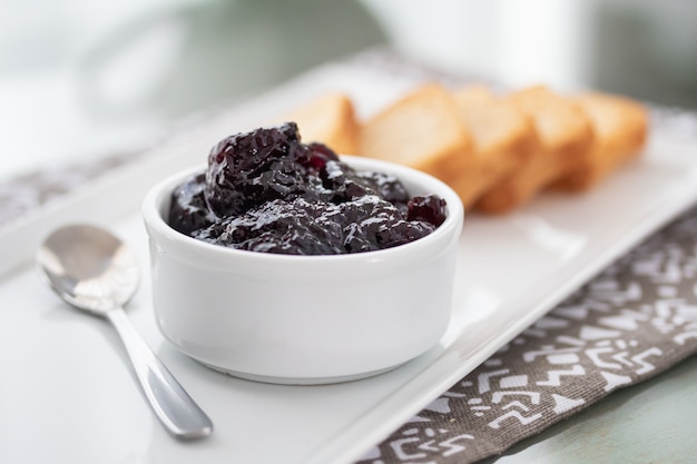 Toasts with cranberries jam and a cup of coffee on white