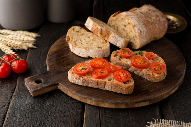 Toasts with tomatoes and bread on a board on wood