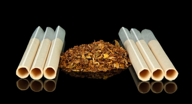 Tobacco and empty cigarette tubes isolated on black