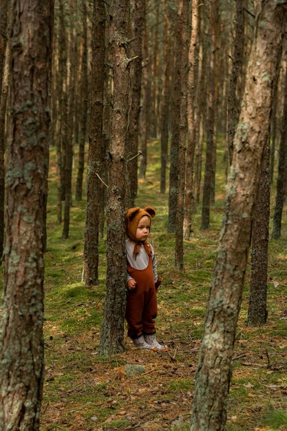 Photo toddler baby boy in bear bonnet sitting in the woods