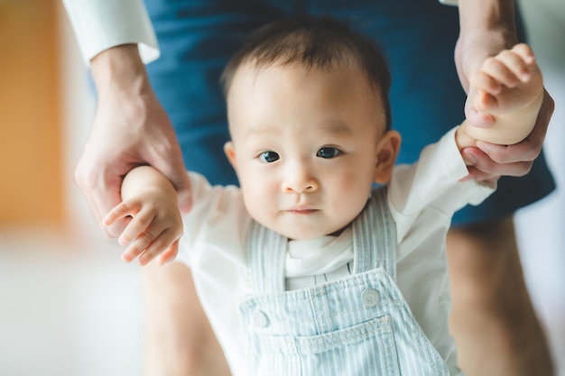 Toddler baby learning to walk and having support by family together little child with father and mother at home with first step to walking by help and holding hand from dad happy childhood help care