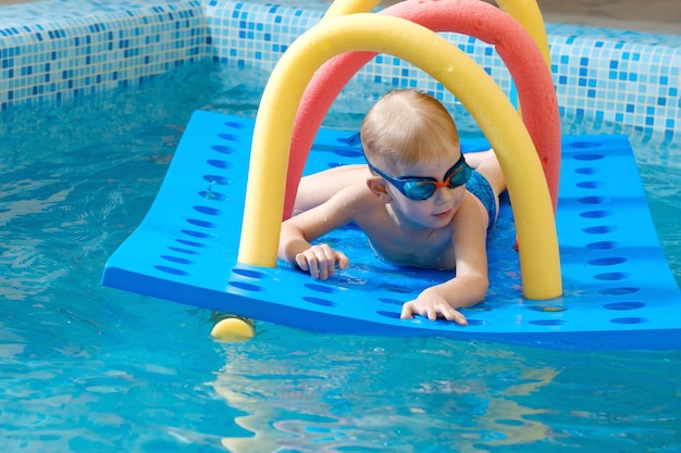 Toddler boy crawling through tunnel on the water in pool