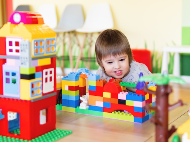 Toddler boy is playing in kidsroom with colorful constructor