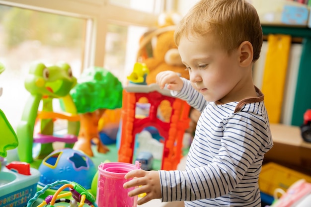 Toddler boy plays with toys in the children's room Educational toys for young children Child one and a half years two years Selective focus