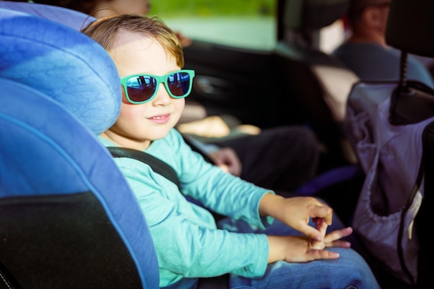 Toddler boy weraing sun glasses sitting in a car seat family travelling by car Preschool child in the auto