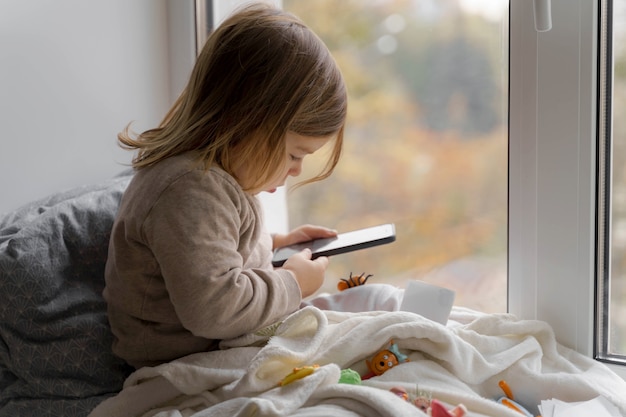 toddler child using phone at home, taking photos and playing games