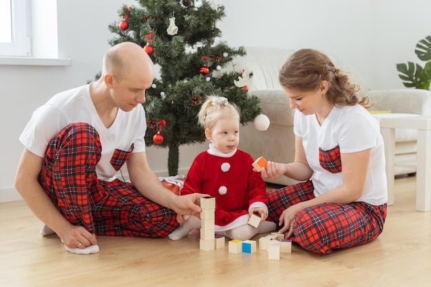 Toddler child with cochlear implant plays with parents under christmas tree deafness and innovating medical technologies for hearing aid and diversity