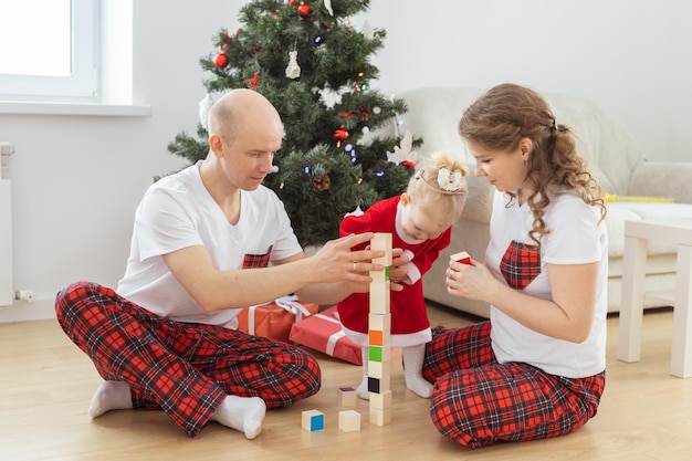 Toddler child with cochlear implant plays with parents under christmas tree deafness and innovating