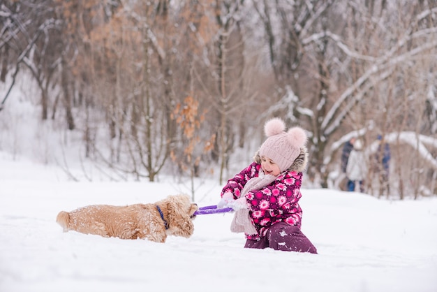 Toddler girl and cocker spaniel having fun during winter