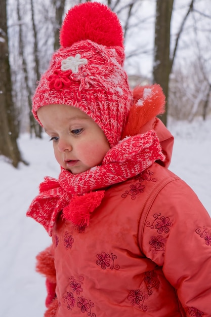 Toddler girl who walking by snow in the park. Frost winter season.