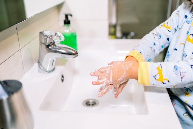 Toddler washing hands with soap to prevent and protect against covid 19 coronavirus