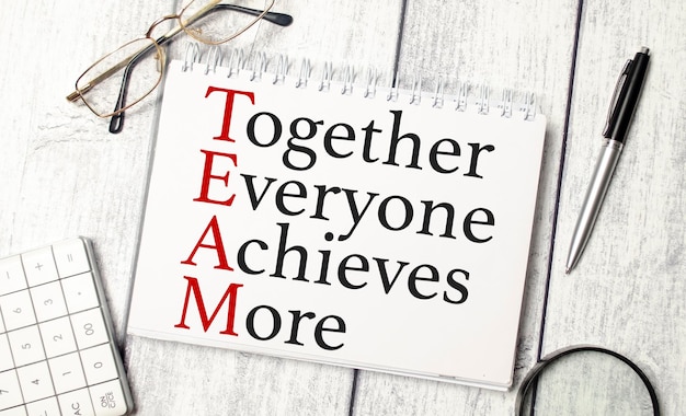 Together everyone achieves more words and calculator pen and glasses on wooden background