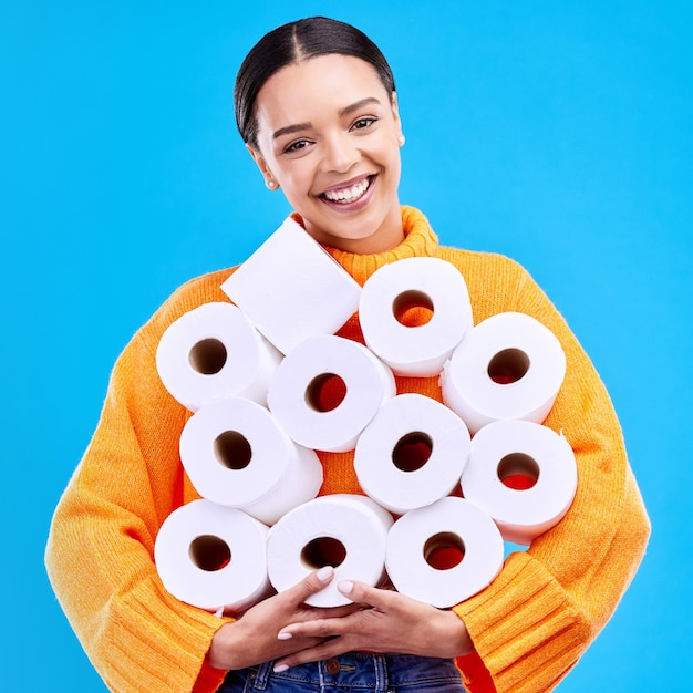 Toilet paper young woman and portrait with happiness and smile in a studio Isolated blue background and happy female person and youth model with tissue rolls stock and gen z fashion smiling